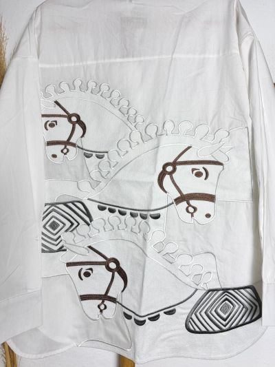 Blusa blanca oversice con caballos bordados en la espalda y bolsillos bordados